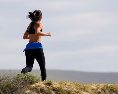 a woman runs accross a cliff top